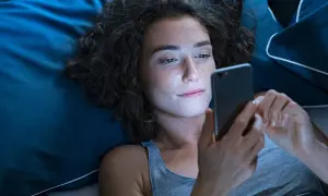 Dziewczyna leży w łóżku, przeglądając telefon. Może szuka wierszy na dobranoc dla dziewczyny, by wysłać je ukochanej.