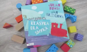 Książka "Klasyka dla smyka" z wierszami Tuwima i Brzechwy, otoczona kolorowymi klockami. Czytanie jej to jak zabawa, a nie jak szukanie karaluchów pod poduchy.