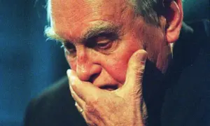 Starzec z dłonią na twarzy, pogrążony w myślach. Jego oczy zdają się opowiadać wiersze o tęsknocie i pragnieniu.