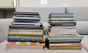 Dwie wysokie sterty książek na kanapie. Zastanawiasz się, czy można oddać swoje książki do biblioteki?