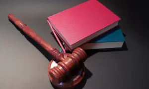 Drewniany młotek sędziowski i stos książek. Jak oddać książki do biblioteki? Zwróć je, zanim zostaną wycofane z obiegu.