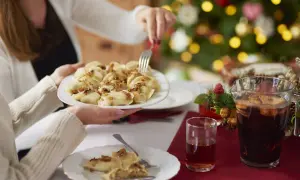 Rodzina przy wigilijnym stole dzieli się pysznymi pierogami. W tle choinka, a na stole kompot. Idealne wierszyki na polaznika!