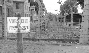 Znak "VORSICHT Hochspannung Lebensgefahr" przy ogrodzeniu z drutu kolczastego. Czy opowiadania Borowskiego to literatura faktu?