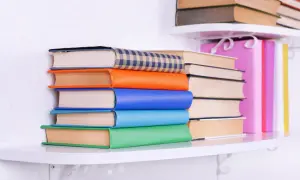 Stos kolorowych książek na półce. Jak naprawić książkę? Wystarczy je uporządkować i cieszyć się lekturą.