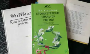 Zielona okładka "Stowarzyszenia Umarłych Poetów" N.H. Kleinbauma. Obok biała książka Walta Whitmana.