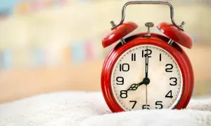 Czerwony budzik na białym tle, pokazuje 8:00. Czas na wierszyk na dzień dobry dla niego!