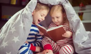 Chłopiec i dziewczynka pod gwiazdkową kołdrą czytają książkę. To idealny wiersz na dobranoc dla chłopaka, pełen przygód i śmiechu.