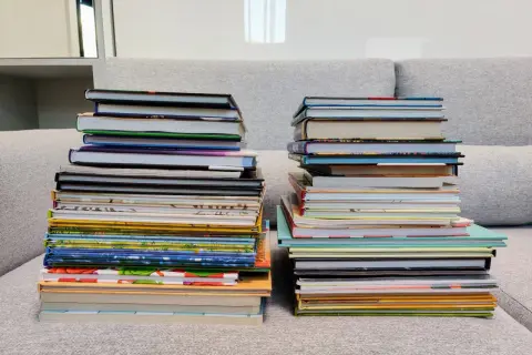 Dwie wysokie sterty książek na kanapie. Zastanawiasz się, czy można oddać swoje książki do biblioteki?