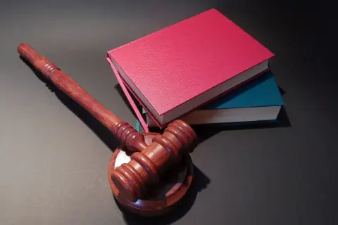Drewniany młotek sędziowski i stos książek. Jak oddać książki do biblioteki? Zwróć je, zanim zostaną wycofane z obiegu.