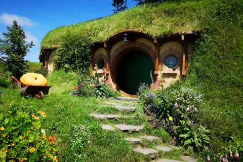 Zielone drzwi i okrągłe okna w zboczu wzgórza, gdzie mieszkał Bilbo Baggins. Obok wielka dynia na taczce.