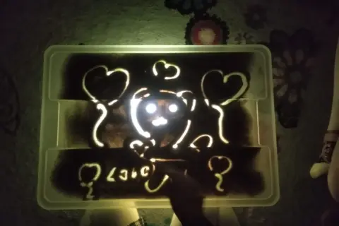 Napis "love" i misia z serduszkami na podświetlanej piaskownicy. Jak piękne smutne wiersze, które można wyczarować palcami.