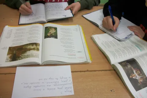 Dzieci piszą w zeszytach, obok leżą otwarte książki z wierszem "Świtezianka". To lekcja polskiego, gdzie analizują, dlaczego Świtezianka jest balladą.