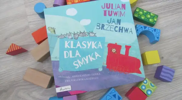 Książka "Klasyka dla smyka" z wierszami Tuwima i Brzechwy, otoczona kolorowymi klockami. Czytanie jej to jak zabawa, a nie jak szukanie karaluchów pod poduchy.