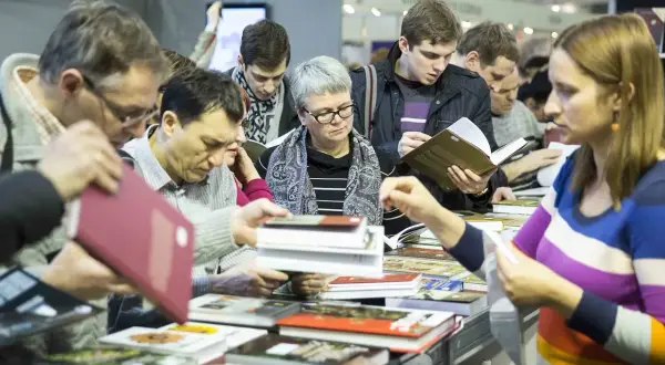 Ludzie przeglądają książki na stoisku, szukając inspiracji, co warto przeczytać z klasyki.