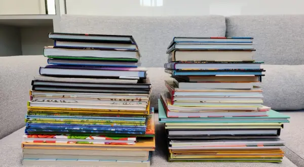 Dwie wysokie sterty książek na kanapie. Zastanawiasz się, czy można oddać swoje książki do biblioteki?