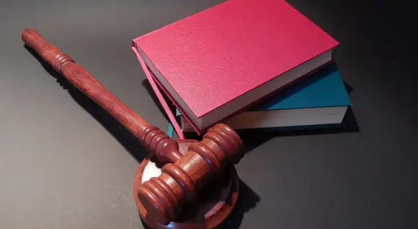 Drewniany młotek sędziowski i stos książek. Jak oddać książki do biblioteki? Zwróć je, zanim zostaną wycofane z obiegu.