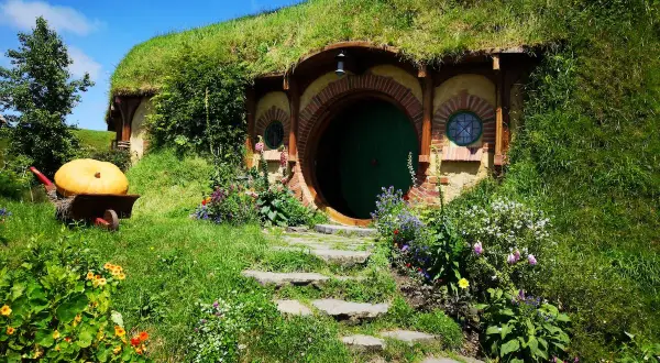 Zielone drzwi i okrągłe okna w zboczu wzgórza, gdzie mieszkał Bilbo Baggins. Obok wielka dynia na taczce.