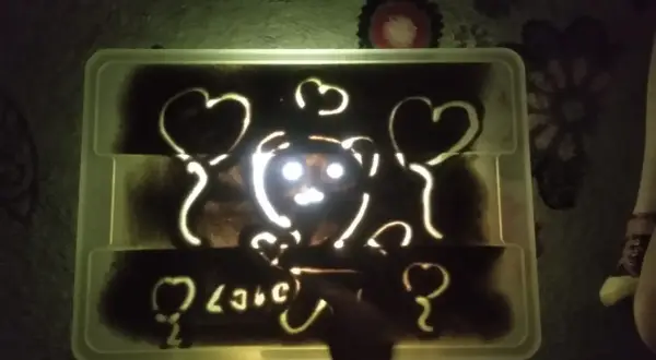 Napis "love" i misia z serduszkami na podświetlanej piaskownicy. Jak piękne smutne wiersze, które można wyczarować palcami.