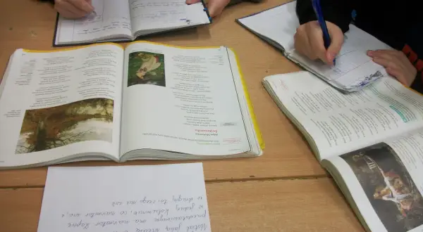 Dzieci piszą w zeszytach, obok leżą otwarte książki z wierszem "Świtezianka". To lekcja polskiego, gdzie analizują, dlaczego Świtezianka jest balladą.