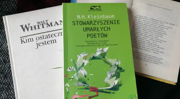 Zielona okładka "Stowarzyszenia Umarłych Poetów" N.H. Kleinbauma. Obok biała książka Walta Whitmana.