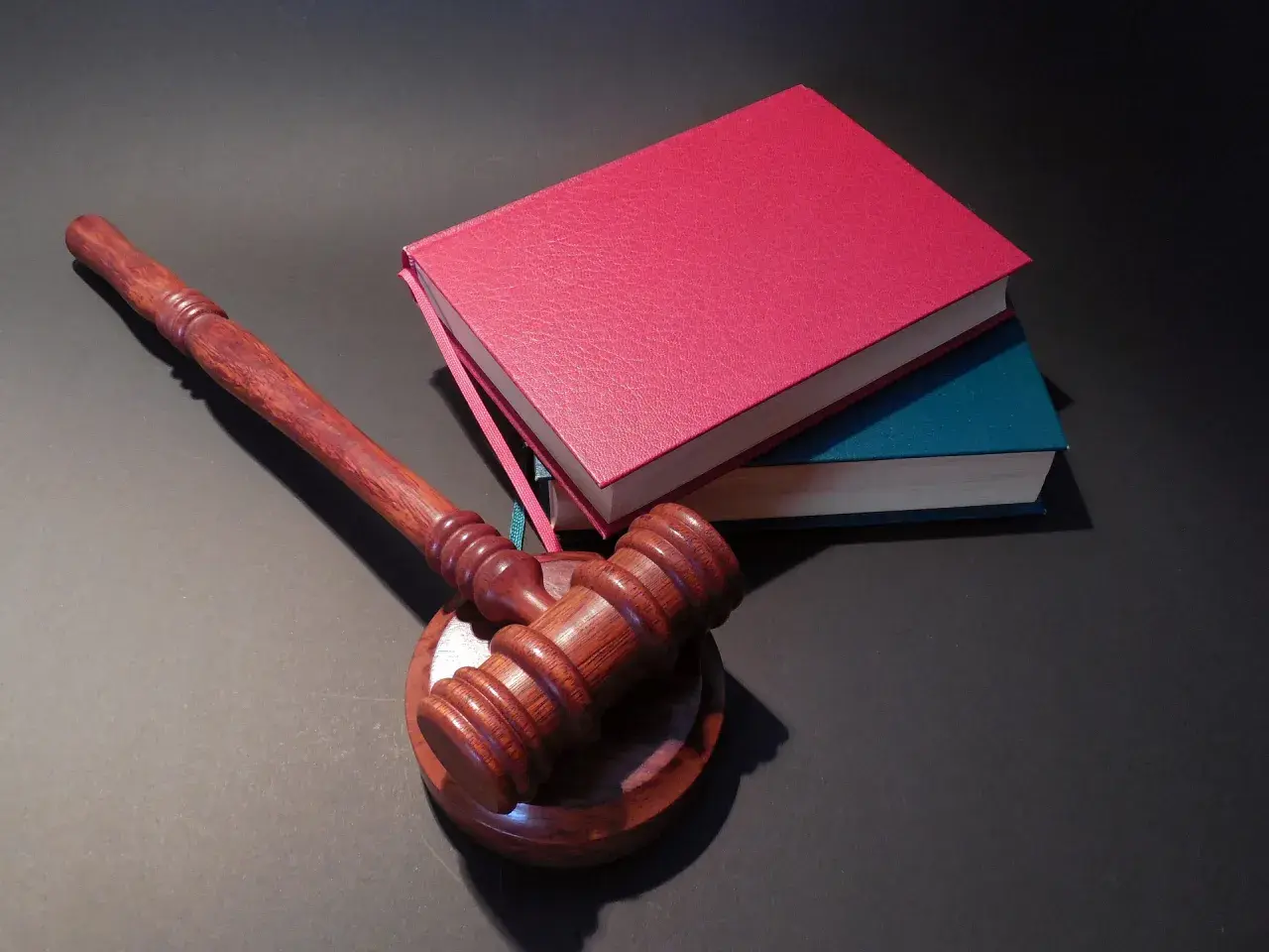 Drewniany młotek sędziowski i stos książek. Jak oddać książki do biblioteki? Zwróć je, zanim zostaną wycofane z obiegu.