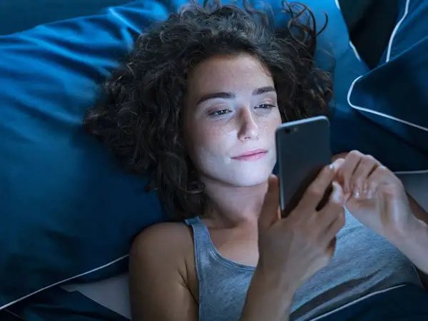 Dziewczyna leży w łóżku, przeglądając telefon. Może szuka wierszy na dobranoc dla dziewczyny, by wysłać je ukochanej.