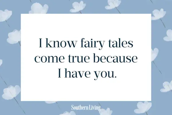 Niebieskie tło z białymi kwiatami i cytatem "I know fairy tales come true because I have you.
