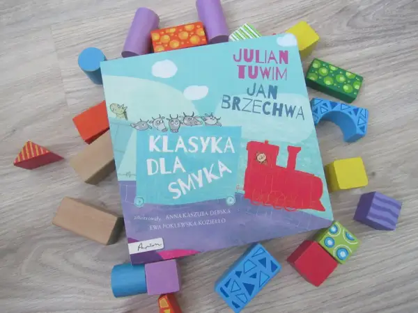Książka "Klasyka dla smyka" z wierszami Tuwima i Brzechwy, otoczona kolorowymi klockami. Czytanie jej to jak zabawa, a nie jak szukanie karaluchów pod poduchy.