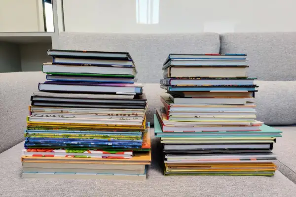 Dwie wysokie sterty książek na kanapie. Zastanawiasz się, czy można oddać swoje książki do biblioteki?