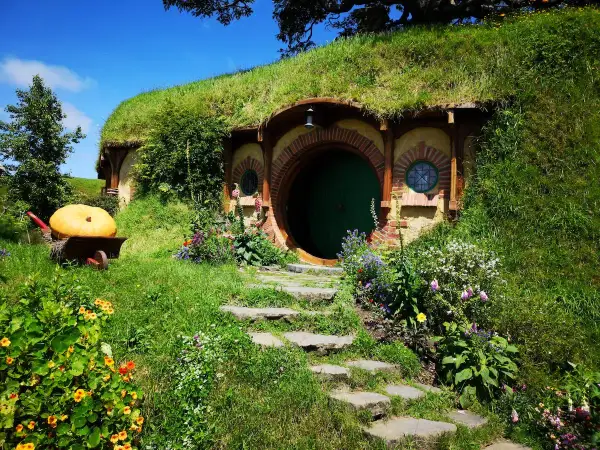Zielone drzwi i okrągłe okna w zboczu wzgórza, gdzie mieszkał Bilbo Baggins. Obok wielka dynia na taczce.