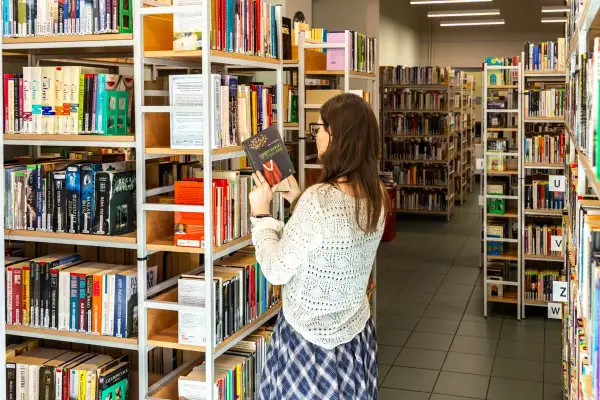 W bibliotece, gdzie **miejscu możecie znaleźć szeroki** wybór książek, młoda kobieta przegląda półki, trzymając w ręku jedną z pozycji.