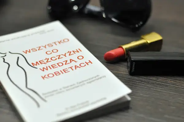 Książka "Wszystko co mężczyźni wiedzą o kobietach", szminka Chanel i okulary przeciwsłoneczne.